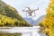 Drone uav flying in the air taking video of autumn forest foliage nature landscape in outdoors during fall season. Quad copter