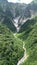 Drone vertical scenery of a trail between terrain of mountain covered with greenery