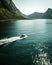 Drone vertical shot of a motorboat sailing in the sea and mountain in the background in Norway