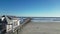 Drone view along the side of a wooden fishing pier traveling towards the blue ocean