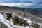 Drone view on a athletic fit woman admires the beautiful winter mountain landscape while standing on the rock.