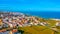 Drone view of a beautiful European city with a hilly landscape on ocean background. Aerial view of a small European town against