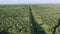 Drone view of a crane travelling on a long road in the desert.