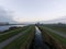 Drone view of a Dutch landscape under a cloudy sky with clouds reflecting on the water at daytime