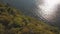 Drone view floating ship in sea on background sunshine reflecting on water surface. Green island and sea waves on stony