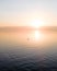 Drone view of golden sky above calm sea at sunset with the silhouette of person rowing a boat