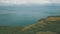 Drone view of a man standing on the hillside against the stunning seascape