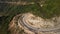 Drone view over a motorist driving along a curvy road on the mountain cliffside.