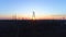 Drone view of power towers, silhouette of electricity power lines and pylons in background of orange sunset