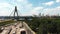 Drone view of riverside with big concrete bridge and group of bike riders crossing through green recreational tourist park