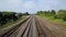 Drone view of rows of long railways laying along green line of bushes and trees