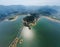 Drone view of shiny blue lake with valley and foggy mountains on horizon under a gray sky