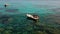 Drone view of Small day boat in the ocean surrounded by crystal clear water with corals and sand