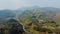 Drone view of valley roads under green fields and foggy mountains under gray sky