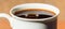 A drop of coffee falls into a white porcelain mug full of freshly brewed coffee