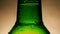 Drop of condensate drains on a green bottle of beer