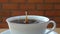Drop fresh milk into a cup of coffee on wooden table