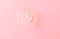 Drop of hydrophilic oil on pink background, top view