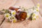 Drop of massage oil in a glass bottle with camomile flowers on w