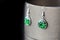 Drop resin earrings with green sparkles on a dark background
