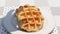 Drop a waffle on another one in a white plate on a table