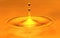 A drop of water falls in a golden water. macro