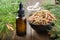 Dropper bottle of essential oil from pine buds, bowl of pine tree buds on table