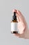 Dropper Bottle Mock-Up. Blank Label - Male hands holding a dropper bottle on a gray background