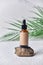 Dropper brown glass bottle on white background with green palm leaves