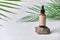 Dropper brown glass bottle on white background with green palm leaves