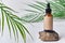 Dropper brown glass bottle on white background with green palm leaves