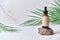 Dropper brown glass bottle on white background with green palm leaves