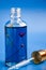Dropper glass Bottle with flowers inside Mock-Up. Cosmetic pipette on blue background. Cuticle oil
