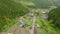 Dropping down over traditional farming village in green forested mountains