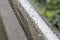 Drops on chrome shiny handrails after rain on a background of green foliage