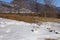 Drops of clean water from Lake Baikal are splashed from a metal aluminum mug on the snow on a picturesque mountain background.