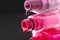 drops of red bearded pink nail polish flow from the bottle of the bottle on a black dark background with a copyspace