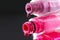 drops of red bearded pink nail polish flow from the bottle of the bottle on a black dark background with a copyspace