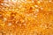 Drops of thick golden honey flowing along the frame of honeycombs. Honey pouring and dripping along honeycomb cells in