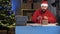 Dropshipping owner male Hindu Santa Claus works at night in his home office, knitting a big red bow on box before