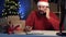 Dropshipping owner male Indian Santa Claus works at home office at night taking order by phone and making notes on paper
