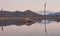 Drought affected dam, barren trees, water smoothed by slow shutter speed