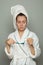 Drowsy woman in white bathrobe holding toothbrush with toothpaste. Morning routine