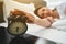 Drowsy young woman touching timepiece with one hand