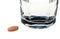 Drug tablet in front of glass of water