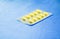 Drug yellow or treatment medication in packages plastic pill. on blue fabric table select focus with shallow depth of field with