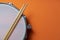 Drum stick and drum on orange table background, top view, music concept