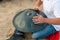 The drummer in action. guy sitting on the sand beach and playing handpan or hang. Hang is traditional ethnic drum