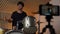 Drummer man plays online and records video on smartphone. A male drummer conducts online training