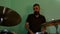 Drummer warming up with drum brushes. Bearded man playing rock and metal music on drums on green wall background 4k